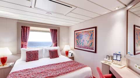A cabin with a bed, desk, and a window overlooking the sea - MSC Opera, MSC Cruises