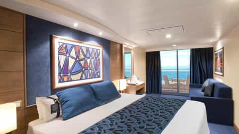 A bed, sofa, and balcony with ocean view - MSC Orchestra, MSC Cruises