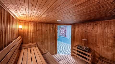 Wooden sauna room with benches and a view into a tiled area - MSC Orchestra, MSC Cruises