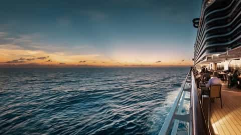 People dine on an outdoor deck at sunset - MSC Seascape, MSC Cruises