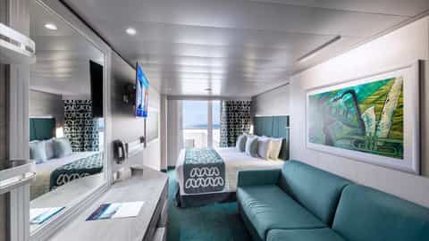 A modern cruise ship suite with a bed, sofa, and balcony - MSC Virtuosa, MSC Cruises