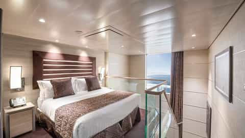 A spacious suite bedroom with a large bed and ocean view - MSC Virtuosa, MSC Cruises