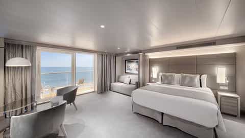 A spacious suite with a bed, seating area, and balcony - MSC World America, MSC Cruises