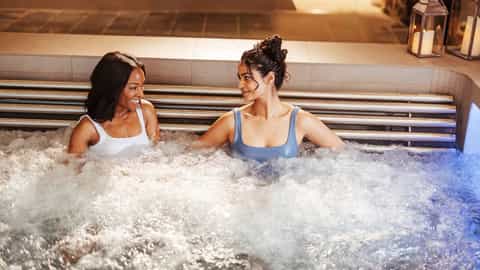Two women relax in a bubbling hot tub - MSC World Asia, MSC Cruises