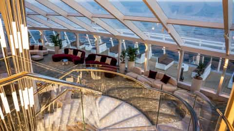 A modern lounge with seating and a spiral staircase - MSC World Asia, MSC Cruises