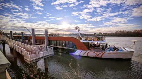 A riverboat is docked at a pier under a cloudy sky - AmaKristina, AmaWaterways