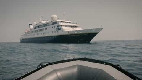 A large ship sails on a calm sea - National Geographic Orion, Lindblad Expeditions