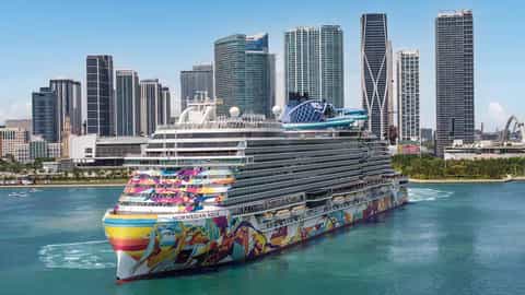 A colorful cruise ship sails past a city skyline - Norwegian Aqua, Norwegian Cruise Line
