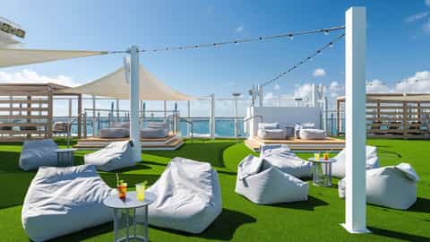 Beanbag chairs and small tables with drinks on a deck - Norwegian Bliss, Norwegian Cruise Line