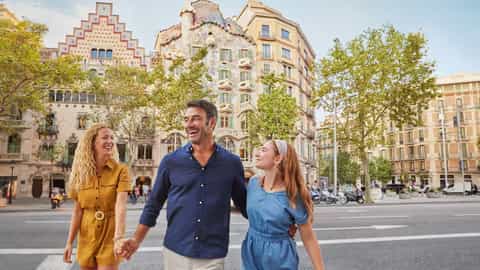 A family walks down a city sidewalk with ornate buildings - Norwegian Escape, Norwegian Cruise Line