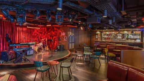 A stage with instruments and a bar area with seating - Norwegian Getaway, Norwegian Cruise Line