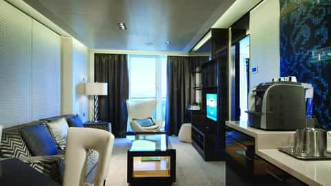 A modern suite living area with a sofa, chair, and coffee table - Norwegian Getaway, Norwegian Cruise Line