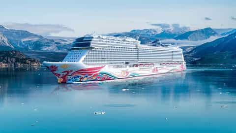 A large cruise ship sails on calm water near mountains - Norwegian Joy, Norwegian Cruise Line