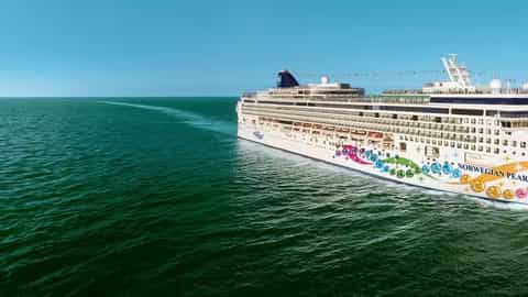 A large cruise ship sails on a calm, blue ocean - Norwegian Pearl, Norwegian Cruise Line