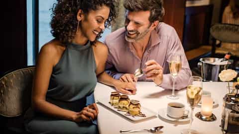 A couple shares a dessert and champagne at a table - Norwegian Star, Norwegian Cruise Line