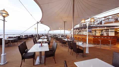An outdoor dining area with tables and a bar - Norwegian Sun, Norwegian Cruise Line