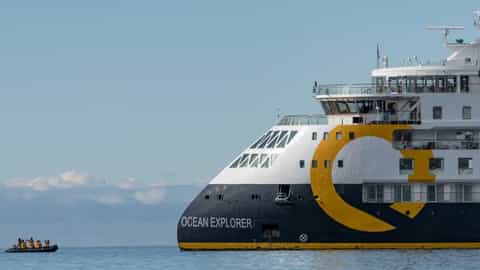 A ship sails on the water under a blue sky - Ocean Explorer, Quark Expeditions