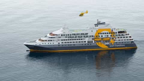 A large expedition ship sails on the ocean with a helicopter overhead - Ocean Explorer, Quark Expeditions