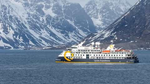 An expedition ship sails by snow-capped mountains - Ocean Explorer, Quark Expeditions