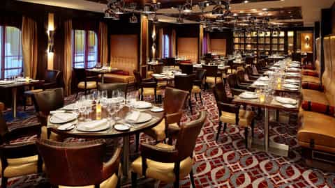 A formal dining room with set tables and leather chairs - Quantum Of The Seas, Royal Caribbean