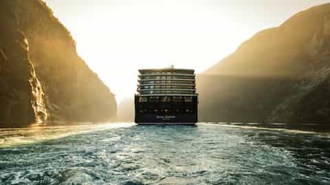 Ship sailing through a fjord at sunset - Queen Elizabeth, Cunard