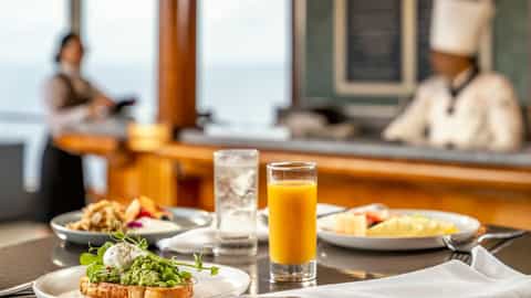 A table set with breakfast dishes and orange juice - Queen Elizabeth, Cunard
