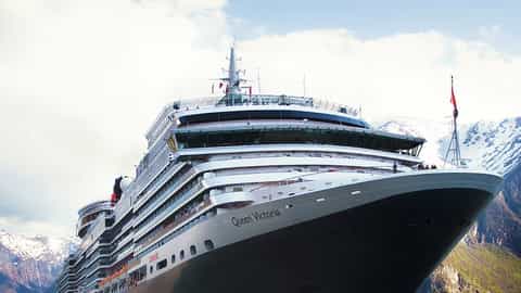 A large cruise ship sails past snow-capped mountains - Queen Victoria, Cunard