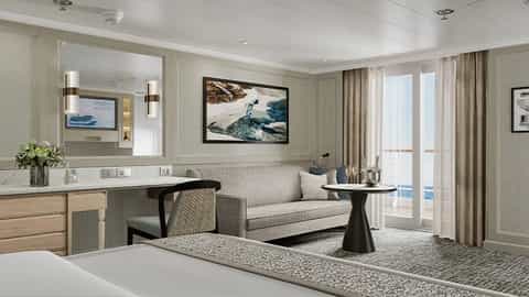 A suite living area with a sofa, table, and balcony access - Regal Princess, Regent Seven Seas Cruises