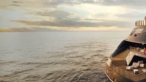 A large ship sails on the ocean at sunset - Ritz-Carlton Luminara, Ritz-Carlton Yacht Collection