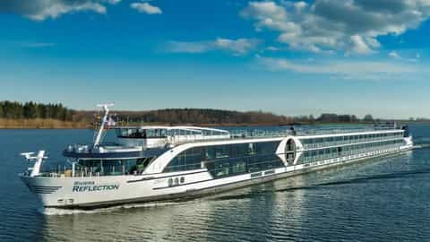 A modern river cruise ship sails on a calm body of water - Riviera Reflection, Riviera Travel