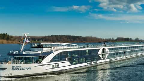 A modern river ship cruises on a calm waterway - Riviera Reflection, Riviera Travel
