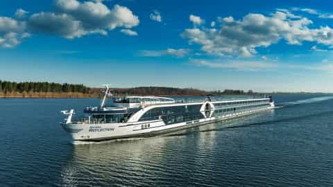 A modern river ship sails on a calm blue river - Riviera Reflection, Riviera Travel