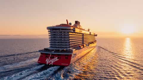 A cruise ship sails on the ocean at sunset - Scarlet Lady, Virgin Voyages