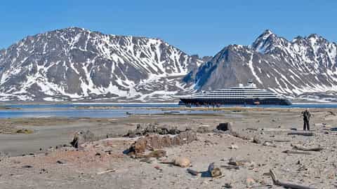 A cruise ship is anchored near a snow-capped mountain range - Scenic Eclipse, Scenic Cruises
