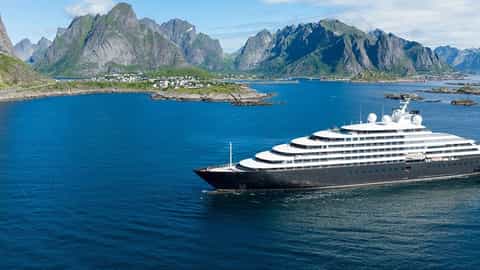 A large cruise ship sails on blue water near mountains - Scenic Eclipse, Scenic Cruises