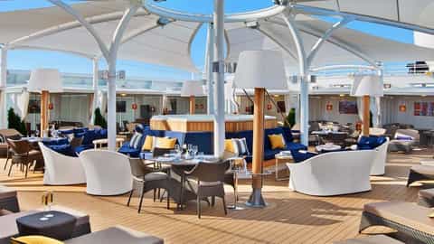An outdoor lounge area with seating, tables, and a hot tub - Seabourn Encore, Seabourn Cruises