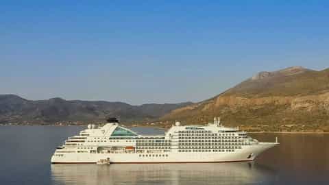 A large white cruise ship sails on calm blue water - Seabourn Encore, Seabourn Cruises