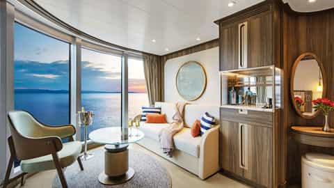 A suite living area with a sofa and large window overlooking the sea - Seabourn Pursuit, Seabourn Cruises