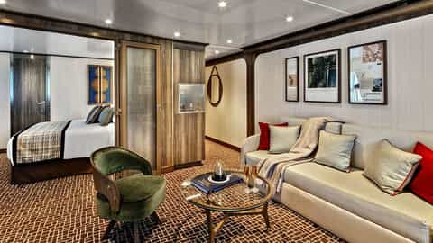 A suite with a bed, sofa, and coffee table - Seabourn Pursuit, Seabourn Cruises