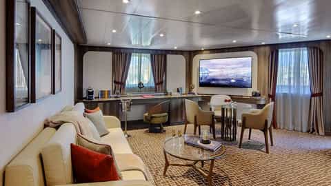 A suite living area with a sofa, chairs, and a television - Seabourn Pursuit, Seabourn Cruises