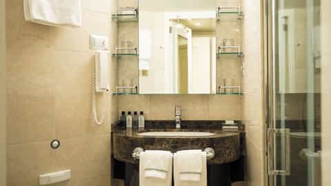A compact bathroom with a marble vanity and glass shower - Seven Seas Explorer, Regent Seven Seas Cruises