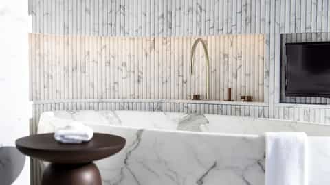 A modern bathroom with a marble bathtub and brass faucet - Seven Seas Grandeur, Regent Seven Seas Cruises