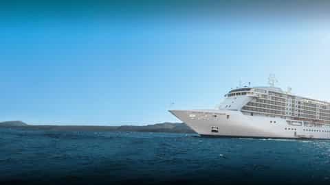 A large white cruise ship sails on the ocean - Seven Seas Voyager, Regent Seven Seas Cruises