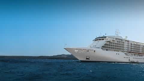 A large white cruise ship sails on the blue sea - Seven Seas Voyager, Regent Seven Seas Cruises
