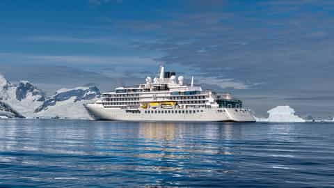 A large cruise ship sails past icebergs and snowy mountains - Silver Endeavour, Silversea Cruises