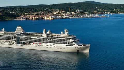 A large cruise ship sails near a coastal town - Silver Ray, Silversea Cruises