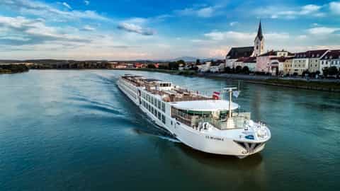 A river ship cruises past a European town - SS Beatrice, Uniworld