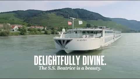 A river cruise ship sails past terraced hills - SS Beatrice, Uniworld