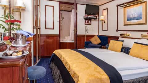 A cruise ship suite with a bed, seating area, and open bathroom - Star Flyer, Star Clippers