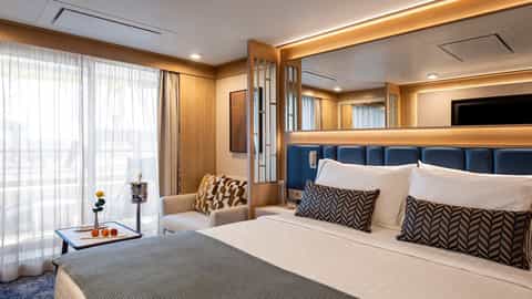 A well-appointed suite bedroom with a bed and seating area - Star Seeker, Windstar Cruises